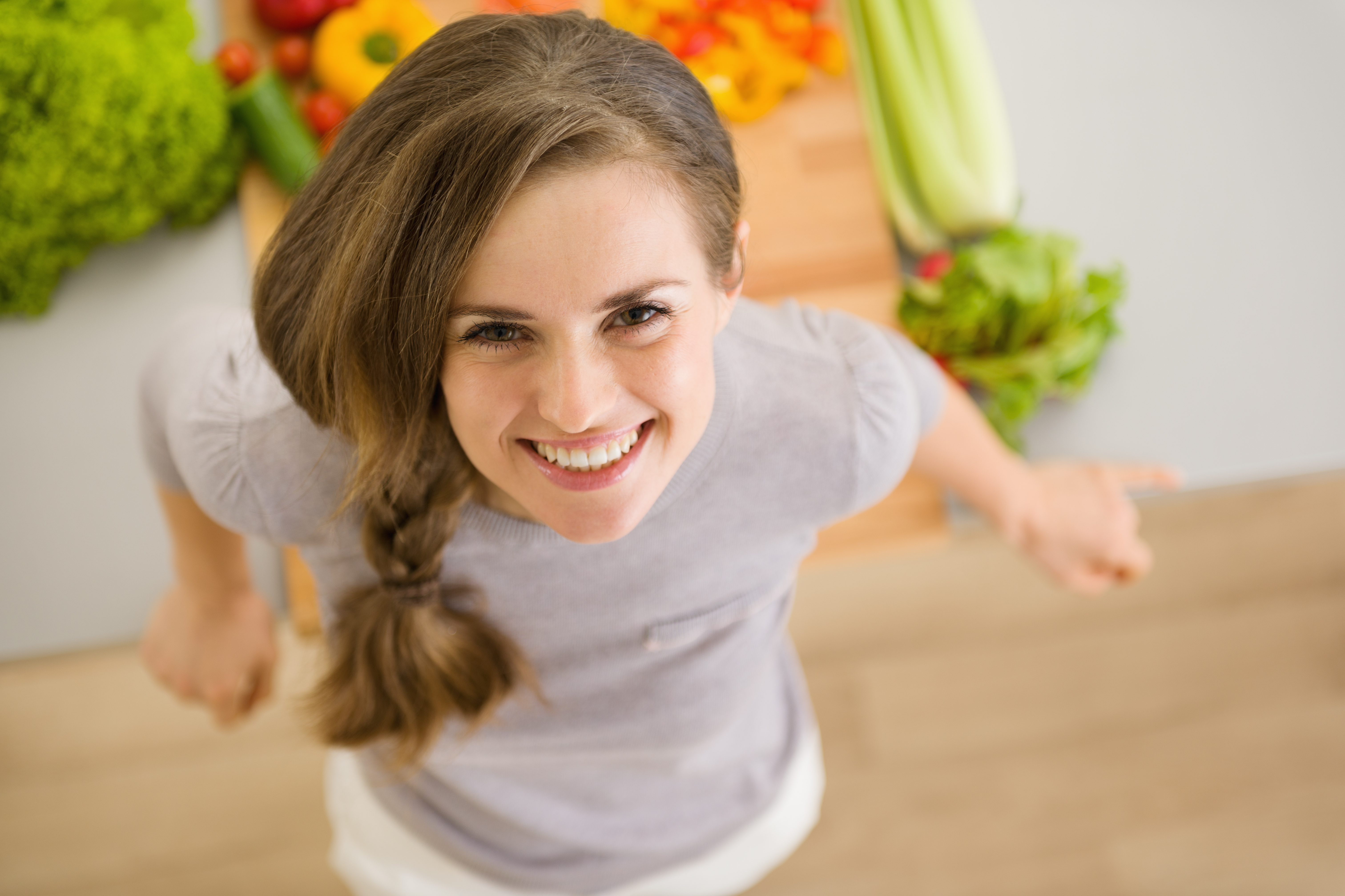 Дівчина з яскравою посмішкою біля столу з овочами