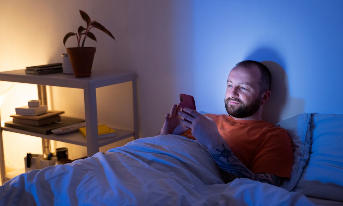 Чоловік зі смартфоном в руках у ліжку у пізній час